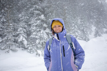 Woman in pink jacket and backpack at winter forest.