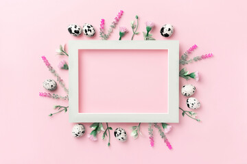 Easter composition. Easter eggs, flowers, paper blank on pastel pink background. Flat lay, top view, copy space.