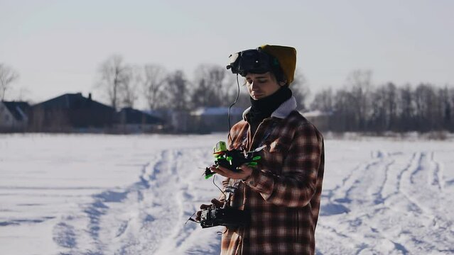 The guy completes the flight on a quadrocopter and catches it with his hand while standing in a field in winter. Shooting in slow motion