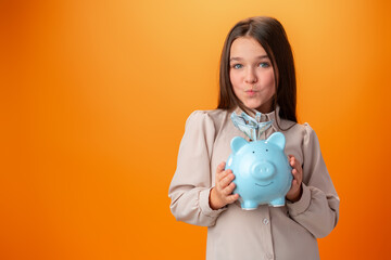 Fototapeta na wymiar Teen girl with piggy bank on orange color background.