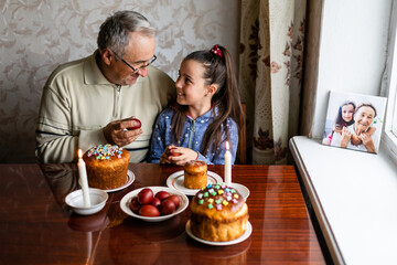 happy grandfather and granddaughter hold easter eggs in hand, folk game beats easter egg
