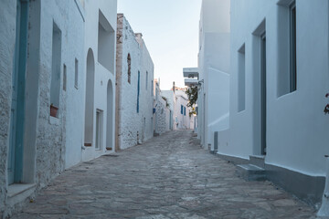 Pano Koufonisi island, Greece. Stonewall building, empty cobblestone street, blue sky background.