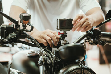 motorcycle mechanic installing action sports camera into motorcycle handle bar at garage...