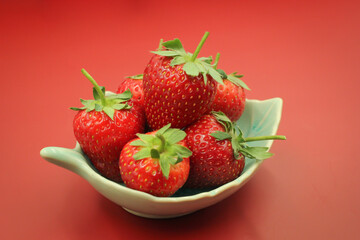 Red strawberries in a bowl. on red background