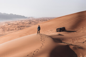 Man walking in huge red desert dunes