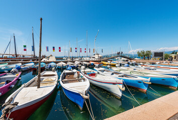 Obraz premium Many fishing and recreational boats moored in the small port of Bardolino village. Tourist resort on the coast of Lake Garda (Lago di Garda). Verona province, Veneto, Italy, southern Europe.