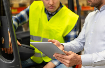 wholesale, logistic, loading, shipment and people concept - close up of loader on forklift and businessman with tablet pc computer at warehouse