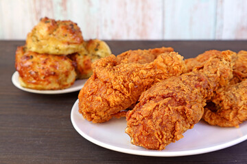 Closeup a Plate of Golden Brown Crunchy Fried Chickens with Blurry Biscuits in Background
