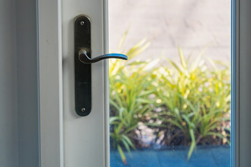 Modern door handle with lock on the white glass door, closeup.