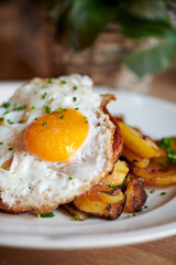 gebratener Spiegelei auf schönen Bratkartoffeln auf weißem Teller serviert.