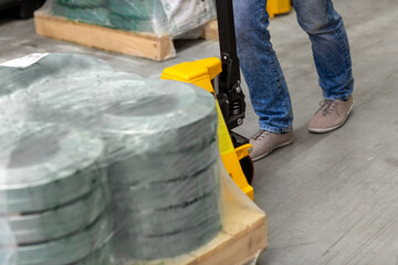 wholesale, logistic, loading, shipment and people concept - close up of man with cargo on loader working at warehouse