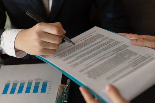 Businessman concept the marketing analyst checking the data on the paper to compare with the information in the graphic for analysis