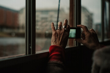 Fototapeta na wymiar Old woman’s hands with rings photographing sights sousing a smartphone 