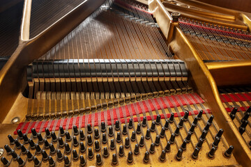 Inside an older grand piano with metal frame, strings, hammer, damper and red felt, mechanics of...