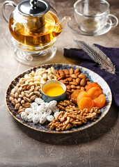 Assorted nuts and dried fruits in oriental style on a platter - dried apricots, cashews,...