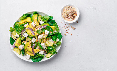Vegetarian salad with avocado, herbs and feta on a light background with space to copy.