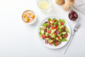 Salad with lettuce, cucumbers, tomatoes, olives and avocados in white plate on the table