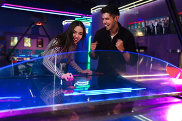 Fototapeta na wymiar White young friends laughing while playing air hockey