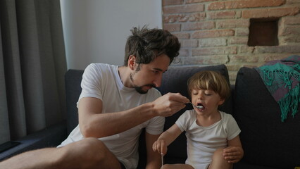 Candid family moment father feeds toddler child yogurt breakfast in morning
