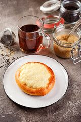 Sweet pies or buns made from yeast dough on platter and glass of tea