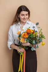 people and floral design concept - portrait of happy smiling woman holding bunch of flowers over beige background