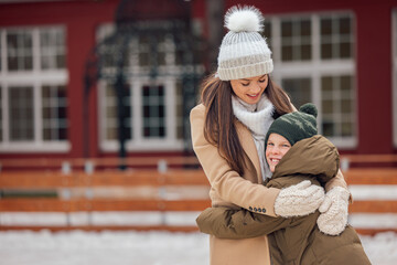 Portrait of people hugging, mom and her child, while taking a break from ice skating.