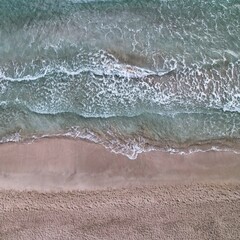 Foto aérea de la arena, mar y olas en Cala Llenya (Ibiza) tomada con dron DJI Air 2S