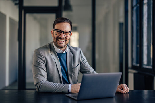 Portrait of lovely caucasian man, preparing his desk for work in the morning.