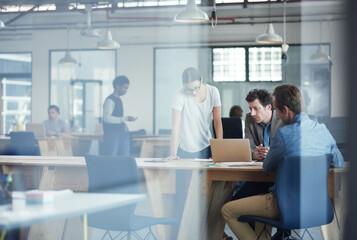 Fototapeta premium Putting there heads together on the project. Shot of a group of colleagues talking together over a laptop in an office.