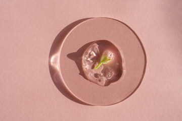 A drop of cosmetic gel with a flower on a pink background.