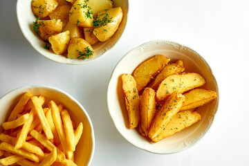 French fries, baked potatoes in slices and boiled in a composition in bowls on a white background.