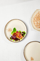 Innovative recipes - salmon cheesecake with parsley oil on handmade ceramic plate. Cheesecake with salmon in modern dishware on white concrete table. Modern food with hard shadow.