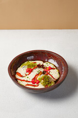 Carrot soup with creamy espuma in dark ceramic bowl. Vegetable cream soup in modern dishware with hard shadow.