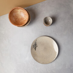Ceramic dishware in modern style on gray stone background. Empty Handmade crockery in minimalistic composition. Pottery plate on concrete background.