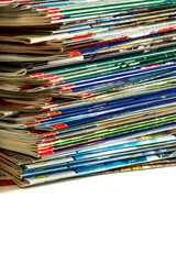 A messy pile of old, colorful magazines on light background.