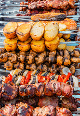 Cooking shashlik on a metal skewer and grilled vegetables. Grilled meat and vegetables. Delicious street food.