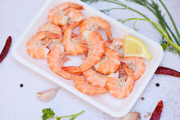 Fresh shrimps on on plate plastic tray with herbs and spices lemon chili on white background, boiled shrimp prawns cooked food in the seafood restaurant
