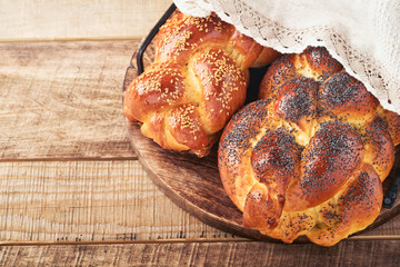 Shabbat Shalom. Bread challah with sesame seeds and poppy seeds on wooden background. Traditional jewish bread for Shabbat and Holidays. Rustic concept. Copy space. Selective focus.