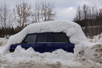 The car is covered in snow. Winter in Russia