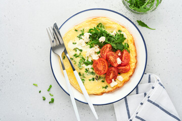Breakfast fried eggs. Rustic omelette or frittatas with green onions, cheese mozzarella, green arugula and tomatoes on light stone background. Healthy food concept. Copy space. Top view. Mock up.