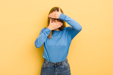 pretty caucasian woman covering face with both hands saying no to the camera! refusing pictures or...