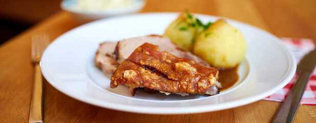 Saftiger krosser Schweinebraten mit Kruste und Knödel mit Sauce 