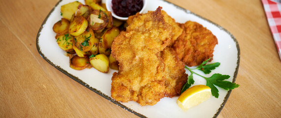 Saftiger Wiener Schnitzel vom Kalb mit wellen Panade und Bratkartoffeln auf schönem Teller 