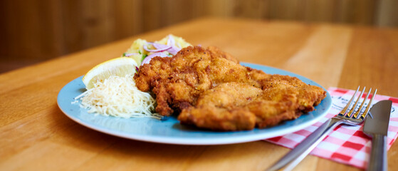 Saftiger Wiener Schnitzel vom Kalb mit wellen Panade und Bratkartoffeln auf schönem Teller 