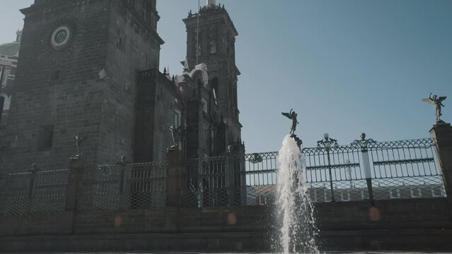 Slow-motion of small fountain in front of historic Puebla Cathedral during summer day,Mexico - close up tilt up