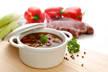 Suppe in weißem Topf  mit Fleisch, Paprika und Fenchel