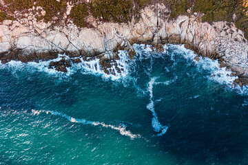 Aerial view of the picturesque scene of sea waves crashing on the rocks. Lonely island in windy weather at high tide