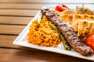 Traditional Turkish Adana kebab or kebap meat food with marinated peppers,  bread and rice pilaf. Top view. Copy space