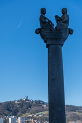 S&auml;ule vor dem Schloss in Linz mit Blick auf P&ouml;stlingberg und blauen Himmel