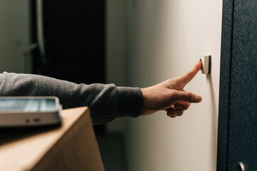 Close-up hands of unrecognizable delivery man ringing doorbell of customer apartment holding...